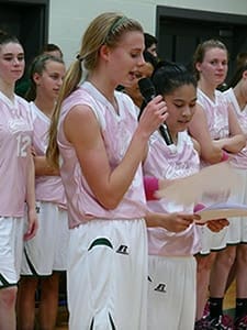Varsity basketball captains Emily Browning, foreground left, and Aimee Sinks, foreground right, make a monetary presentation to St. Joseph Mercy Care following the Feb. 1 PINK Game.