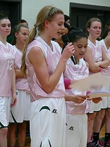 Varsity basketball captains Emily Browning, foreground left, and Aimee Sinks, foreground right, make a monetary presentation to St. Joseph Mercy Care following the Feb. 1 PINK Game. 