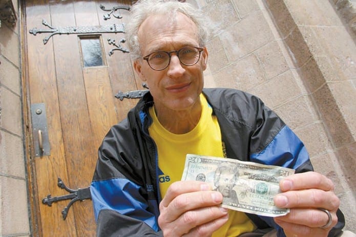 Dr. Joseph Stavas, 58, holds up a $20 bill April 16, with the words “God is Good” written on it. He found it crumpled in his running shorts the day after the deadly explosions at the Boston Marathon. Stavas, who ran the marathon with his physician-daughter, reflects on her heroism in helping victims, talks about the need for prayer and the inspiration from the Lord to get through it.