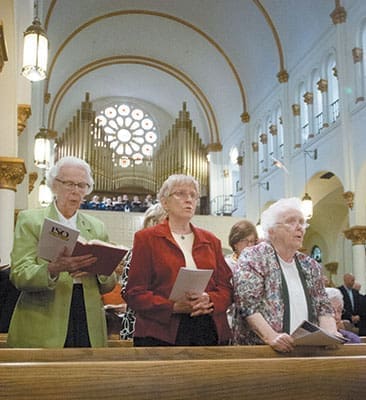 Three religious sisters join the assembly in song at the Mass of Thanksgiving on April 14 at the Basilica of the Sacred Heart of Jesus in Atlanta. Shown, left to right, are Mercy Sister Denis Marie Murphy, Sister Jeanne Urschel, CSJ, and Sister Margaret McAnoy, IHM, vicar for religious. The Mass recognized 150 years of Marist ministry in the United States.