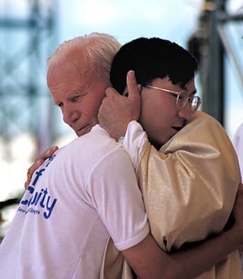 Pope John Paul II embraces a young man during the 1993 World Youth Day in Denver. The pontiff instituted the international gatherings that attract hundreds of thousands of Catholic young people to a different city every two or three years. (CNS file photo)
