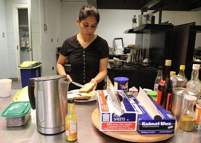 Standing in the kitchen, Rubina Tabassum of India butters her toast as she prepares to eat breakfast before departing to work. (Photo By Michael Alexander)