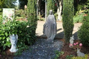 A statue of Mary (Our Lady of Grace) is displayed among the peony, zinnia, and other flowers and bushes. (Photo By Michael Alexander)