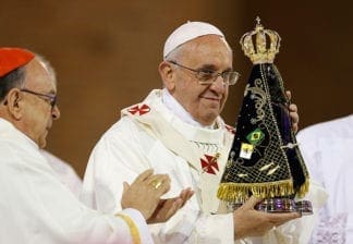 Pope Francis holds up a statue of Our Lady of Aparecida after it was presented to him by Cardinal Raymundo Damasceno Assis of Aparecida, left, at the beginning of Mass at the Basilica of the National Shrine of Our Lady of Aparecida July 24.