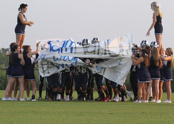 The team runs through the banner, held by cheerleaders, less than a minute before kickoff of the school’s inaugural regular season football game. The banner read “RAM NATION It’s a way of life.”