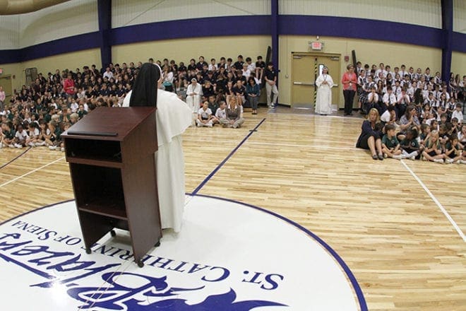 Principal and Dominican Sister Mary Patrick, standing in front of the podium, leads everyone in a prayer of thanksgiving following her announcement that St. Catherine of Siena is a 2013 National Blue Ribbon School. It is the only Catholic school among the eight Georgia schools recognized by the U.S. Department of Education. Photo By Michael Alexander
