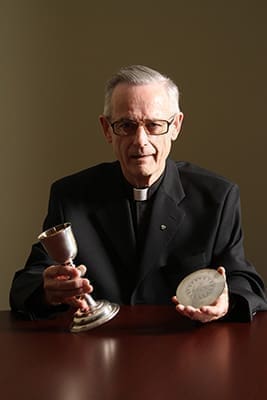 Recently retired Father John Kieran holds the 18th century silver chalice and paten that’s been in his possession for over 50 years. Upon retirement Father Kieran, who currently lives in residence at the Cathedral of Christ the King, Atlanta, donated the sacred pieces to the Archdiocese of Atlanta’s Archives and Records. Photo By Michael Alexander