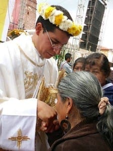 A woman kisses the hand of Father Luis Simon Gallardo as he is welcomed to celebrate his first Mass in his home parish in Mexico Sept. 2.