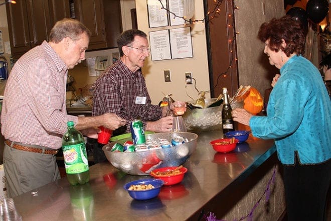 (L-r) Max Tapley of Roswell and Jerry Palombi of Marietta serve an assortment of libations to guests like Nancy Korzeniewski of Johns Creek attending the October Widowed Helping Others social. Photo By Michael Alexander