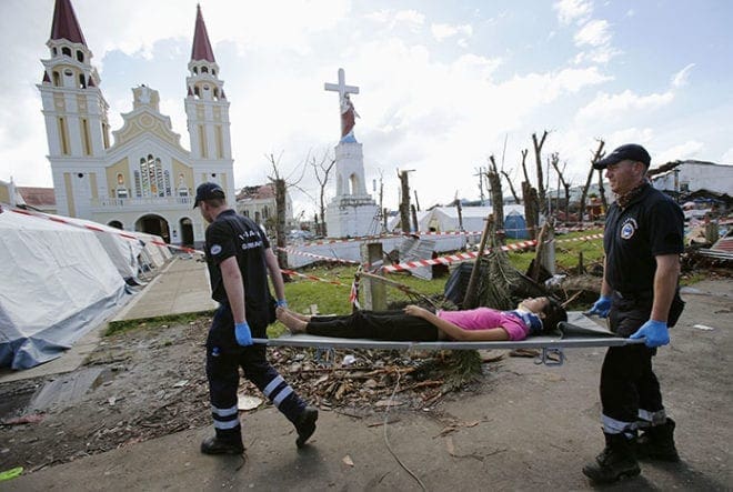 Members of International Search and Rescue, a German agency, carry a patient injured in a motorcycle crash on a stretcher, into their makeshift hospital in the yard of the Metropolitan Cathedral in Palo, Phillipines, Nov. 15. A team of 24 doctors, nurses, rescuers and logistic experts from Duisburg, Germany, are in the Philippines to help the survivors of Super Typhoon Haiyan. CNS photo/Wolfgang Rattay, Reuters