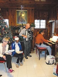 Jimy Kucera plays the accordion as David Caron plays the organ for a Christmas party at Gift of Grace House, in Atlanta.