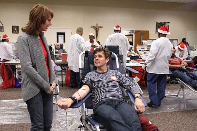 Chris Buechner, the youngest of Bob Buechner’s seven children, donates a pint of blood during the fourth annual blood drive at Holy Cross Church, Atlanta, as his wife Jill stands at his side. Photo By Michael Alexander 