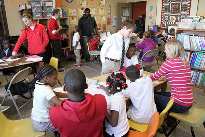After arriving from school, the students and participants in Action Ministries Atlanta’s program for children have a snack and then they do their homework. On this particular day St. Jude the Apostle School students and volunteers like Vincent Pope, standing, background center, were on hand to provide help. Pope is a fifth-year senior and biomedical engineering major at the Georgia Institute of Technology, Atlanta. Photo By Michael Alexander