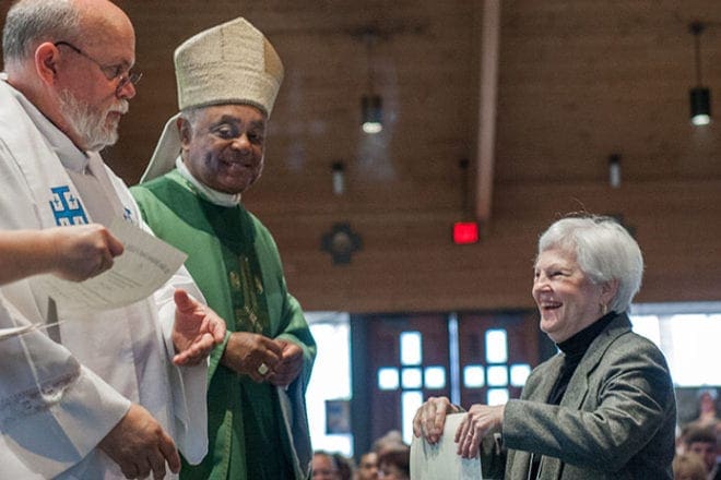 Chaplain for the AACCW, Father Bill Williams, left, assists Archbishop Wilton D. Gregory in presenting the woman of the year certificate to Margie Patterson of Our Lady of the Assumption Church, Atlanta. Photo by Thomas Spink