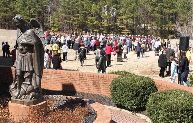 Following the noon Mass, parishioners and clergy make their way to the site of the groundbreaking, a piece of land between the current St. Michael the Archangel Church and Arnold Mill Road. Photo By Michael Alexander