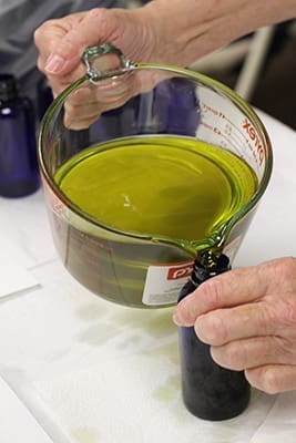 Heidi Bergmann, pours the oil of the catechumens into a blue, four-ounce, plastic bottle. This is the first year of the color-coded distribution system. The oil of the sick and the sacred chrism were poured into clear and amber bottles, respectively. Photo By Michael Alexander 