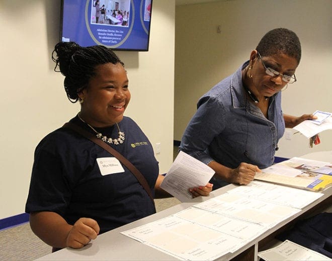 Mya Millines, left, checks in at the main desk, where she received a T-shirt like other incoming students on hand for Cristo Rey Atlanta Jesuit High School’s Mass of dedication. Photo By Michael Alexander 