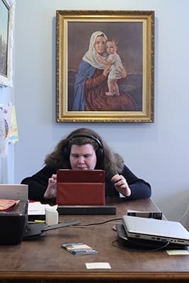 Twenty-two-year-old Caroline Studer works with technology at St. Mary's Independent Living Extensions, Lilburn, as an image of the Blessed Mother and Christ Child hangs over her shoulder. Photo By Michael Alexander