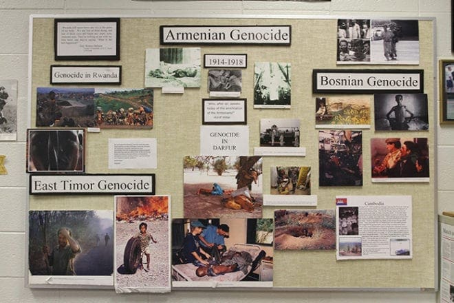 A bulletin board in Dennis Ruggiero’s St. Pius X High School classroom in Atlanta draws attention to the various conflicts and genocides of the past. Photo By Michael Alexander