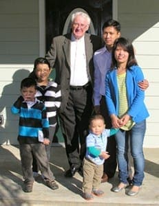 Father Francis Richardson, pastor of Good Shepherd Church in Cumming, stands with the Pauk family in front of their new home. The family helped build their home along with Habitat-North Central Georgia’s volunteers and sponsors. It was the 250th home constructed by the nonprofit organization.