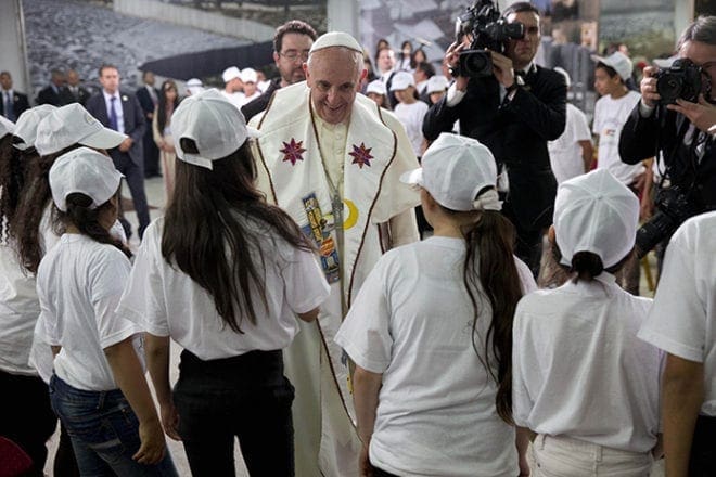 Pope Francis is greeted by young people during a meetingMay 25 in the Dehiyshe Refugee Camp's Phoenix Cultural Center, near Bethlehem, West Bank. Pope Francis told Palestinian refugee youths to look to the future and to always work and strive for the things they wanted. CNS photo/Andrew Medichini, pool via Reuters