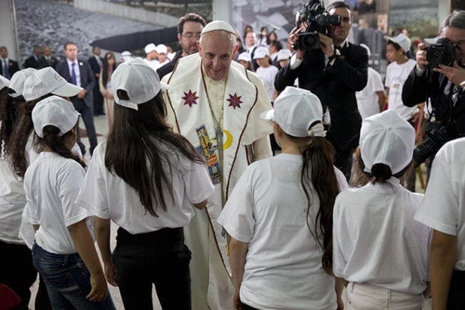 Pope Francis is greeted by young people during a meetingMay 25 in the Dehiyshe Refugee Camp's Phoenix Cultural Center, near Bethlehem, West Bank. Pope Francis told Palestinian refugee youths to look to the future and to always work and strive for the things they wanted. CNS photo/Andrew Medichini, pool via Reuters 