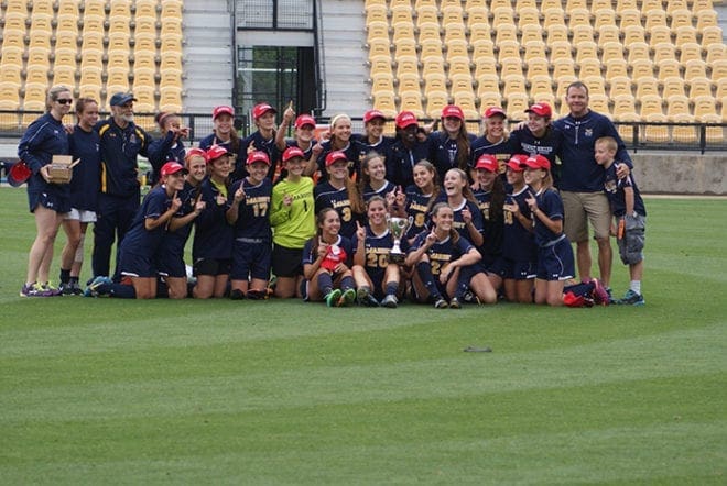 Marist School head coach Sergio Stadler, standing, third from left, joins assistant coaches Julie Rogers, far left, and Chandler Yount, second from right, and the team for a post game photo. The girls soccer team won its second consecutive Class AAAA state championship with a 3-0 victory over Veterans High School of Kathleen.