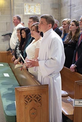(First row, foreground to background) Transitional diaconate candidate Branson Hipp stands in the pew with his parents Jan and Mark, his sister Miah, his paternal grandmother Rita and his uncle Dave. His grandmother and uncle traveled from Evansville, Ind., to attend the May 31 ordination. Photo By Michael Alexander