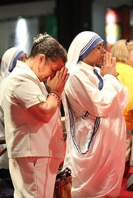 Maria Diaz and Missionaries of Charity Sister Maxmilina kneel in prayer during the healing service that followed the opening Mass of the 2014 Eucharistic Congress. Both women reside at the Gift of Grace House in Atlanta. Photo By Michael Alexander