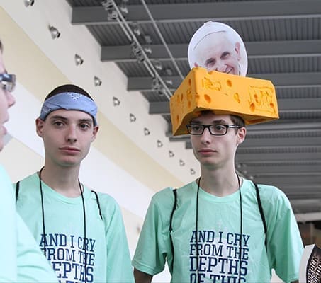 Alex Weidman, right, stands with his 18-year-old twin brother Kyle as they converse with friends. The Little Chute, Wis., native topped off his cheese hat with a photo of Pope Francis. Eighty-six teens and 19 adults traveled from the Diocese of Green Bay to be at the Steubenville Atlanta Conference. Photo By Michael Alexander