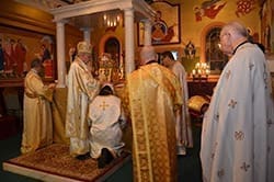 During the ordination rite, Bishop Nicholas Samra, (second from left) head of the Melkite Eparchy of Newton, Massachusetts, places the end of his omophorion (one of his vestments) over the head of Deacon Elie Hanna and says the prayer of ordination. The ceremony included texts in English, Arabic and Greek. Photo by Cindy Connell Palmer