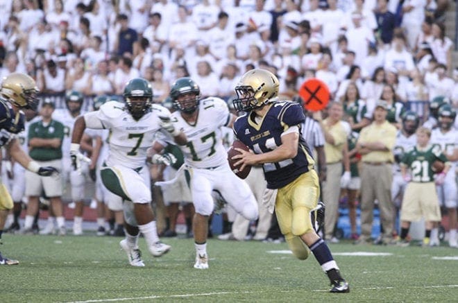 St. Pius X quarterback Joey Connors (#11) roles out to the left as Blessed Trinity defensive tackle Shane Parton (#7) and outside linebacker Logan Craighead give pursuit from the right side during the Aug. 29 game, the season opener for both teams. Blessed Trinity won 42-20. Photo By Michael Alexander