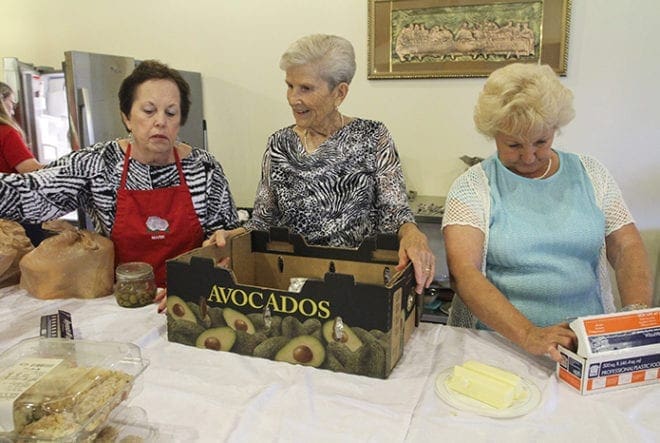 (L-r) Marie Thurmond, president of the women’s guild, and fellow members Mari Benson and Gail Thomas gather food for a parish family in a show of support following an Aug. 23 funeral and repast at the church. The funeral was followed by a wedding, a quinceañera and the Saturday vigil Mass. Photo By Michael Alexander