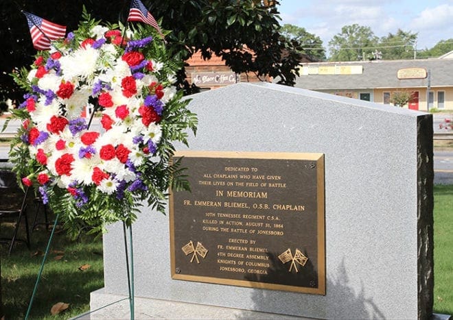 A wreath of flowers is displayed at the memorial on the grounds of the historic courthouse in Jonesboro, honoring Civil War chaplain and Benedictine Father Emmeran Bliemel. August 30 marked the 150th anniversary of his death. Photo by Michael Alexander