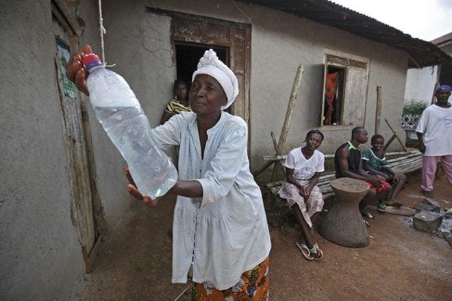 To curb the spread of Ebola, a Liberian woman washes her hands using a bottle of chlorine water in Jene Wonde, a village near the border with Sierra Leone, Nov. 9. CNS photo/Ahmed Jallanzo, EPA