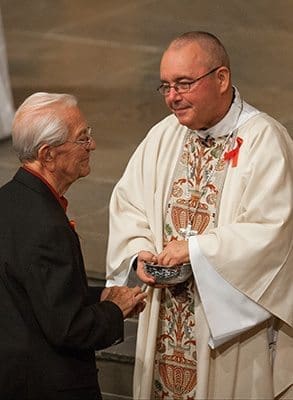 Jim Martino, whose son, Mark, died of AIDS in 1993, receives Communion from Bishop David P. Talley at the archdiocesan World AIDS Day Mass. The Martinos are members of St. Philip Benizi Church and he was a lector at the Mass. Photo By Thomas Spink