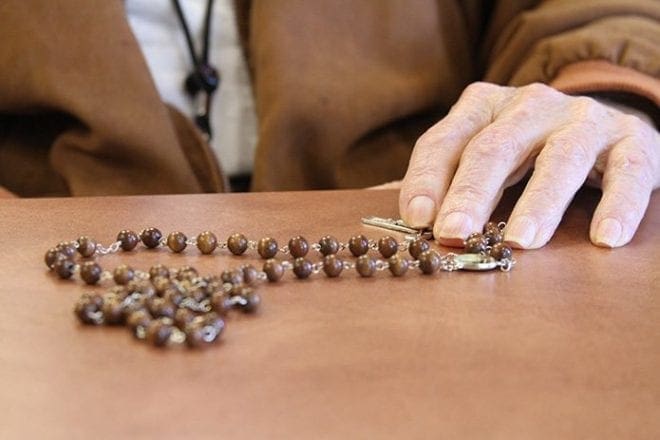 Larry Clancy, 86, caresses the cross on his rosary at St. George Village’s Wellington Court, Roswell. Clancy is one of the 11 or more residents who routinely participate in the Saturday morning recitation of the rosary. Photo By Michael Alexander