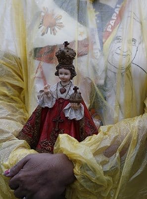 A woman holds a statue of statue of Santo Nino, the Holy Child Jesus, as Pope Francis celebrates Mass at Rizal Park in Manila, Philippines, Jan. 18. The Mass was celebrated on the feast of Santo Nino and texts at the Mass were those of the Philippines for the feast day. CNS photo/Paul Haring