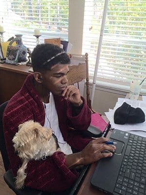 As his Maltese Yorkie Layla sits in his lap, Norman Francis Jr., a Blessed Trinity High School junior, works on his assignments during the school’s virtual school days last Oct. 22-23.
