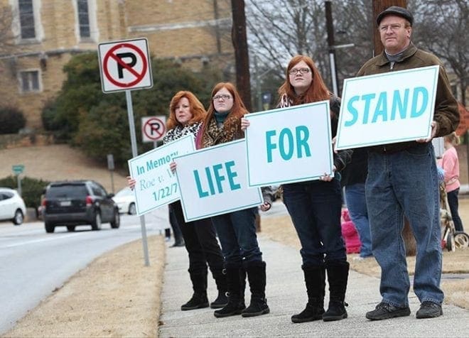 (R-l) Bill Bennett stands with his 14-year-old twin daughters, Clara and Sarah, and his wife, Becki, as they hold signs on the east side of Peachtree Road during Stand for Life, Jan. 22. The Bennetts are parishioners at St. Anna Church in Monroe. Jan. 22 is the anniversary of the 1973 Supreme Court decision legalizing abortion in the United States. Photo By Michael Alexander
