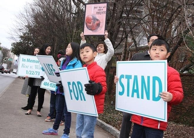 Parents and children from the Holy Vietnamese Martyrs Church in Norcross hold signs along the west side of Peachtree Road during Stand for Life. Photo By Michael Alexander