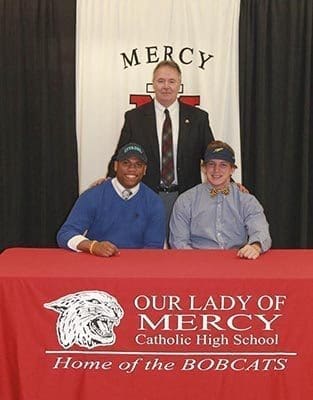 Our Lady of Mercy High School football coach Mike Earwood stands with two of the school’s football signees. Jordan Thomas, left, signed a letter of intent with The Citadel, Charleston, S.C., and Jameson Vest signed a letter of intent with the University of Toledo, Toledo, Ohio.