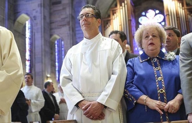 Ordination candidate Christopher Andronaco, left, stands with his wife of nearly 37 years, Denise, during the processional hymn. Photo By Michael Alexander