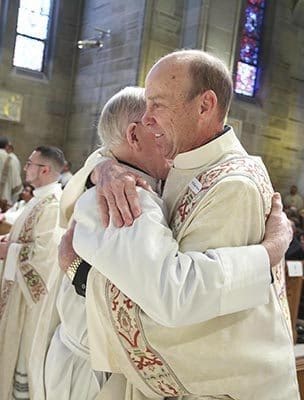 Deacon William Brown of St. Mark Church in Clarkesville receives the sign of peace from his brother deacons. Photo By Michael Alexander