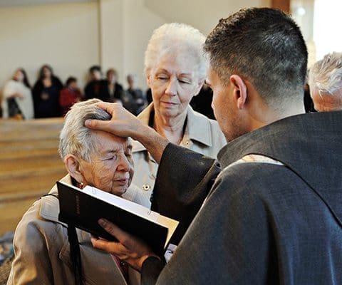 Following the reception, Father Gabriel Scasino returned to the sanctuary to offer blessings. Here he blesses parishioners Betty Hale and Lorraine McAdoo. Photo By Lee Depkin