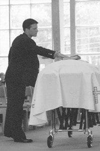 This image of John Timme, shot on film, was published in the Oct. 3, 2002 issue of The Georgia Bulletin, along with the story of his father’s death. During the funeral John is returning his father’s Bible to the casket after sharing some words about his dad, who was ordained a deacon for the Archdiocese of Atlanta in 1987. Photo By Michael Alexander