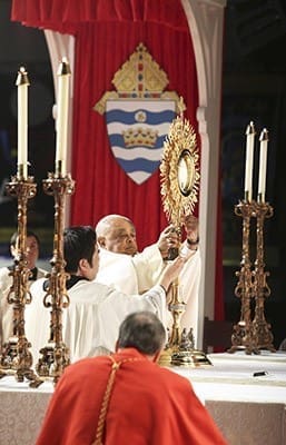 With assistance from Father Diosmar Natad, Archbishop Wilton D. Gregory places the monstrance holding the Real Presence of Jesus in the Eucharist on the altar during the Saturday morning service at the 2014 Eucharistic Congress. Photo By Michael Alexander