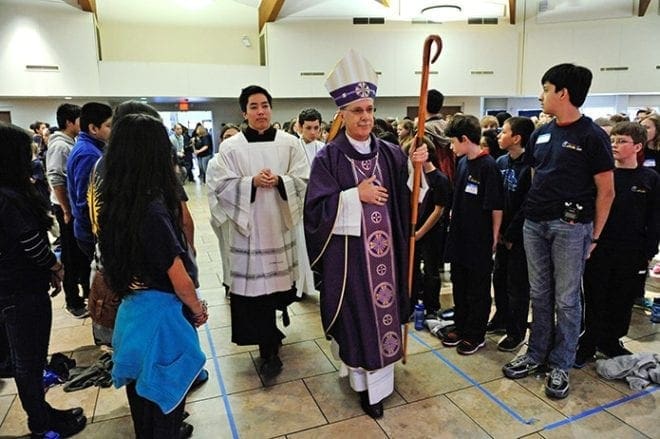 Bishop Luis R. Zarama was the celebrant for the closing Mass at the March 7 Middle School CatholicFest, held at St. John Neumann Church, Lilburn. Shown left of Bishop Zarama and serving at the Mass is John Huynh, youth ministry coordinator for the Archdiocese of Atlanta. Photo By Lee Depkin
