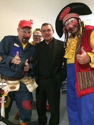 Father Dairo Rico, parochial vicar at Holy Trinity Church in Peachtree City, shares a moment posing with clowns who entertained children during the annual community Health Fair at the parish. The entertainers are from New Hope Baptist Church, in Fayetteville.