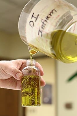Cathedral of Christ the King parishioner Linda Rozakis pours the oil of the sick into clear, four-ounce, plastic bottles for the various archdiocesan parishes. Photo By Michael Alexander